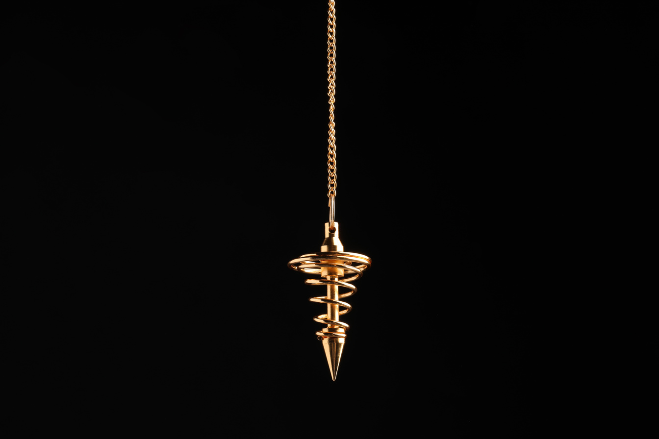 Beautiful Golden Pendulum with Chain on Black Background. Hypnosis Session